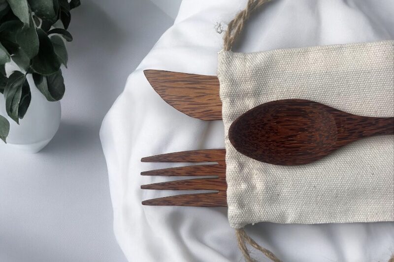 Détail du couvert en coco et son étui en lin pose sur une nappe en tissu blanc
