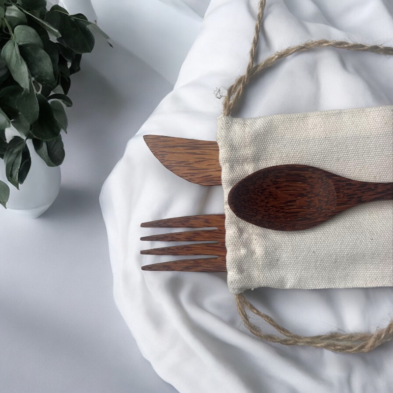 Détail du couvert en coco et son étui en lin pose sur une nappe en tissu blanc